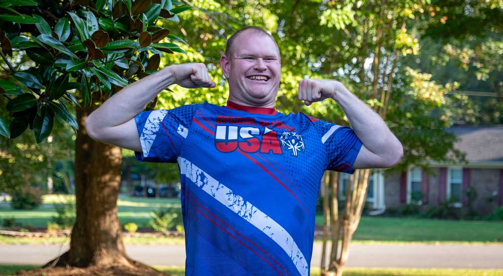 josh myers outside holding up arms and smiling 