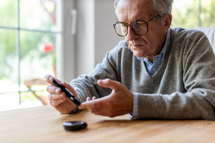Elderly man checks his blood sugar