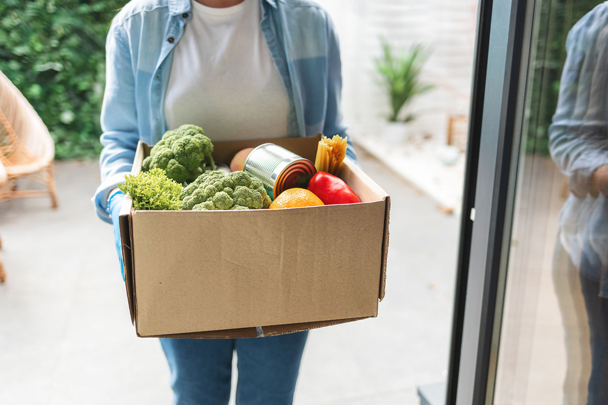A person carries a box of fresh produce 