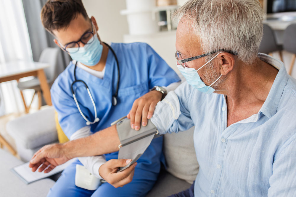 doctor wearing a mask takes blood pressure of patient in mask