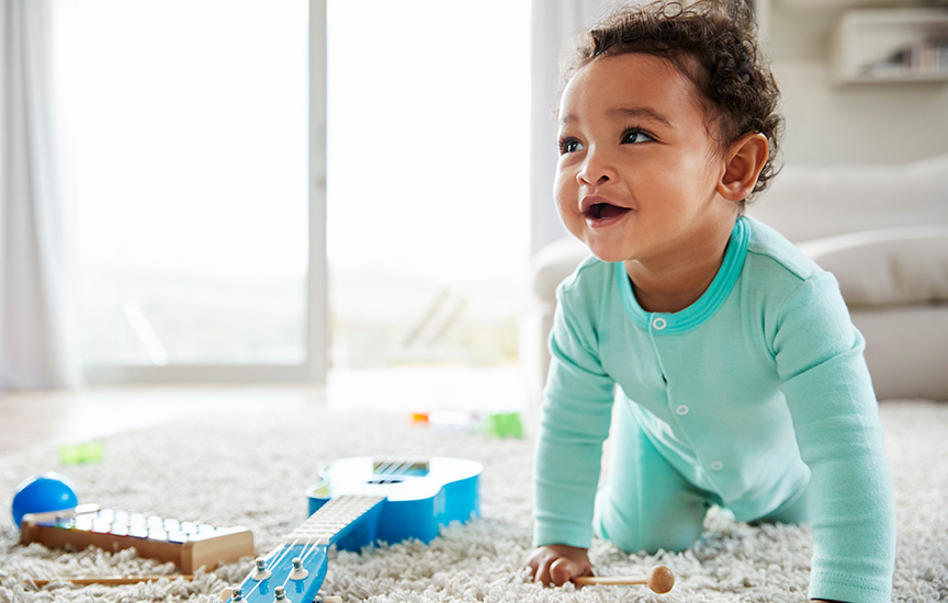 A baby boy joyfully playing with colorful toys on the floor, surrounded by a cheerful atmosphere.