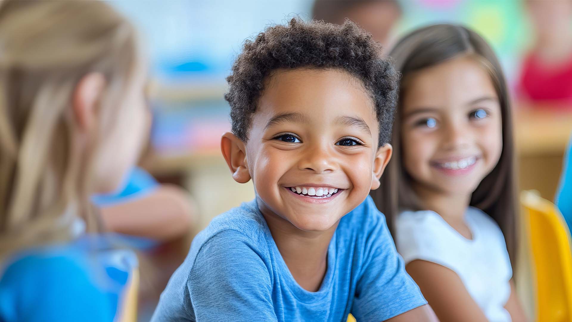 A group of smiling children gathered in a bright classroom, engaged and happy during a learning activity.