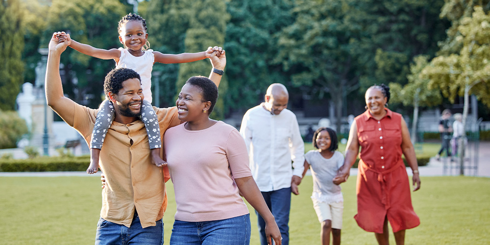 A family of four strolls together in a lush park, enjoying a sunny day surrounded by greenery and nature.