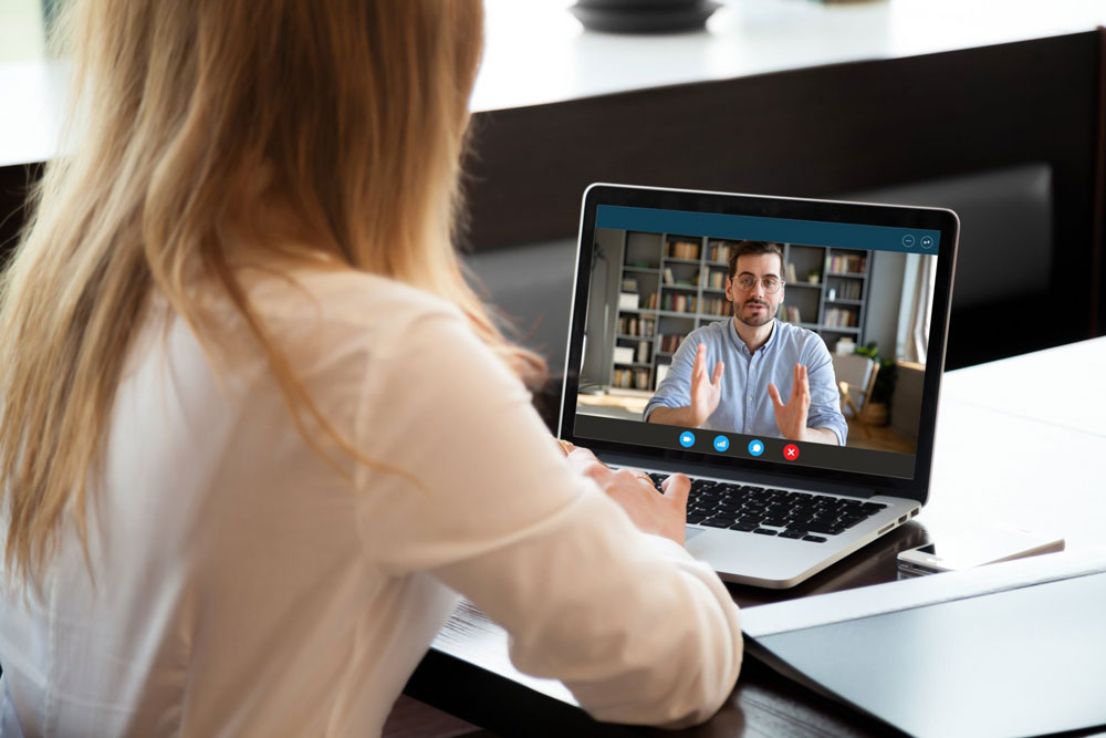 woman looking at computer screen with therapist