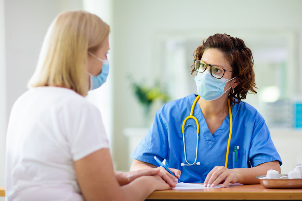 doctor wearing stethoscope talks with patient at table
