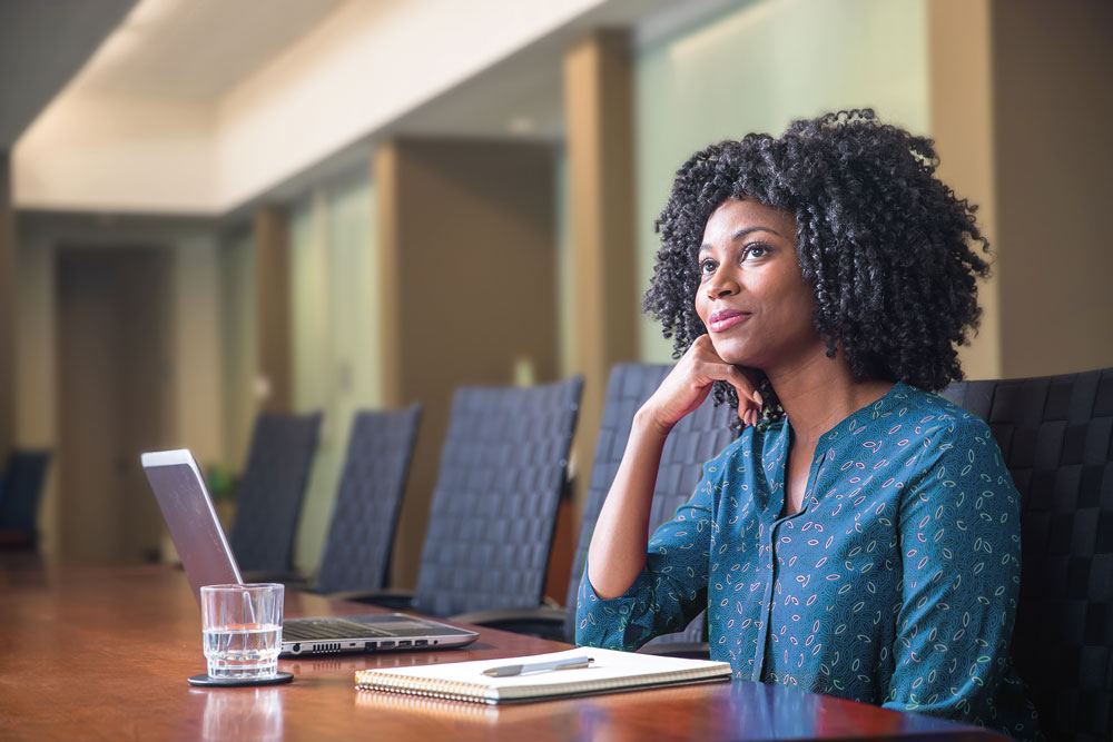 woman sits at conference table with computer