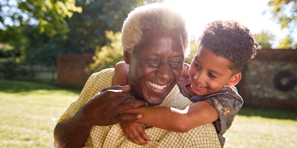 A joyful older man and a young boy share a smile together, capturing a heartwarming moment between generations.