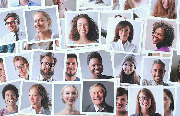 Headshots of people of different genders and ethnicities are spread out over a surface.