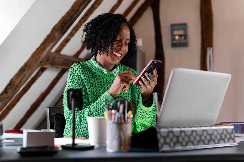 woman sitting at desk with laptop and phone