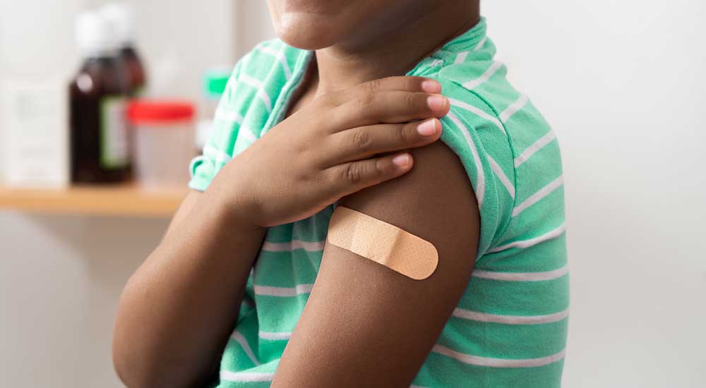Close up of kid arm with bandage from vaccine