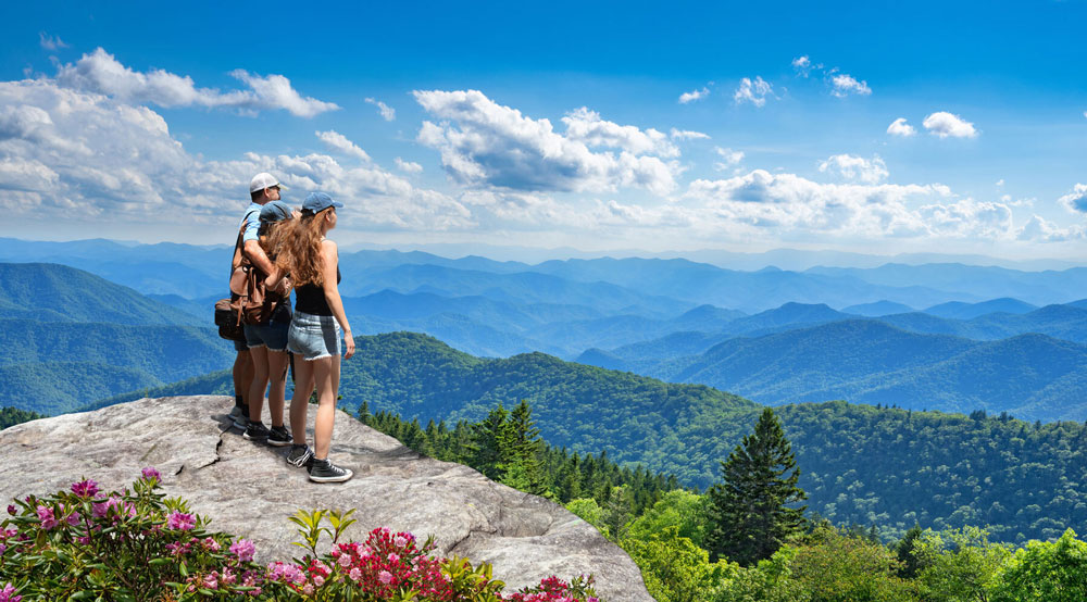family standing on top of mountain with other mountains in background