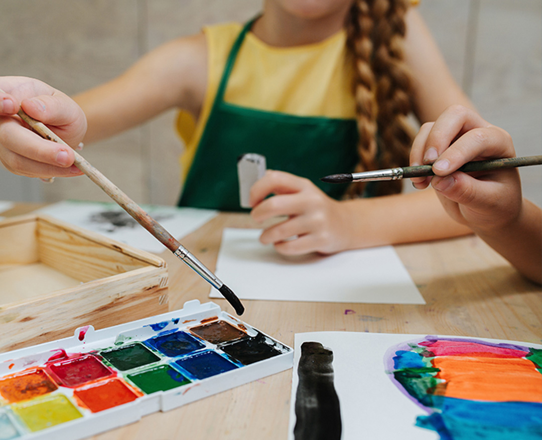 A child sits at a table and paints with watercolors.