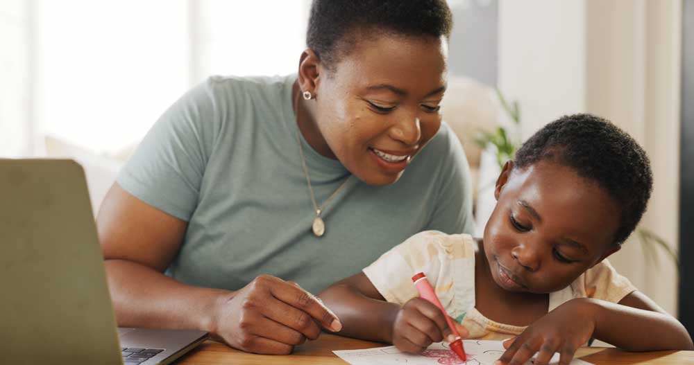 Woman and little girl at table with crayon and paper