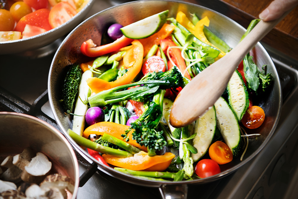 A colorful mix of vegetables sizzling in a pan on a stove, filling the kitchen with delicious aromas.