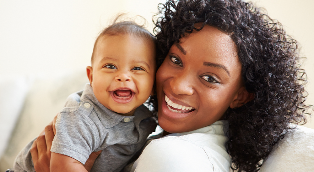 Happy mother holding her baby, both with big smiles.