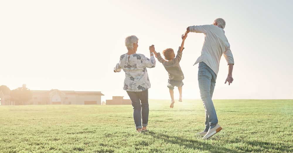 elderly man and woman holding little boy in field