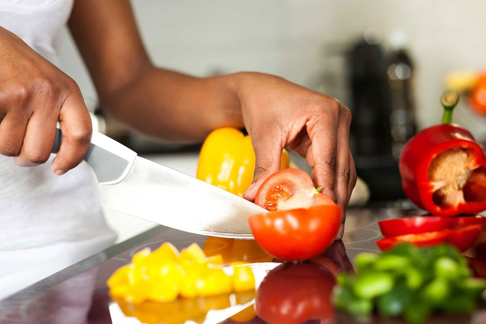 woman cuts fresh  vegetables with knife