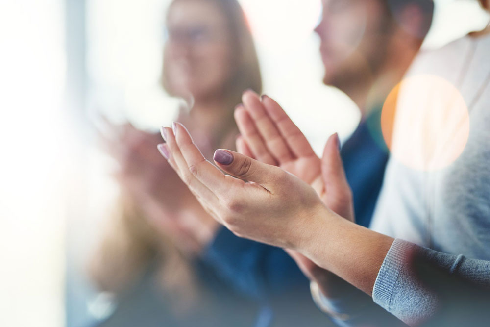 close up of hands clapping with people in background clapping